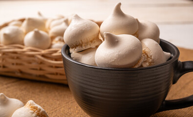 Sweet meringue, a Brazilian sweet called suspiro made with egg whites and sugar, positioned on rustic fabric and accessories, selective focus.