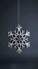 Minimalist wooden snowflake ornament hanging on dark grey background