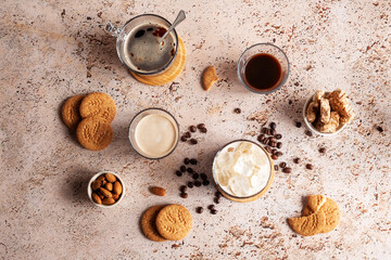 Different types of coffee drinks with cookies on a beige table, top view. Iced coffee, espresso, espresso with milk, brew coffee with almond and whole grain cookies