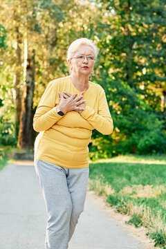 portrait of a senior woman exercising and running outdoors having chest or stomack or hip or back pain or injury