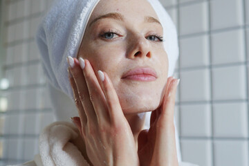 Woman In Bathrobe Gently Applying Moisturizing Mask In Peaceful Bathroom Setting For Glowing Skin