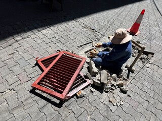 A worker changes a damaged Grid in the pave way in La Paz, Bolivia on a warm and sunny November day. 
