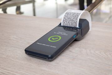 OS terminal with printed receipt and thank you message displayed on screen, illustrating completed retail payment process