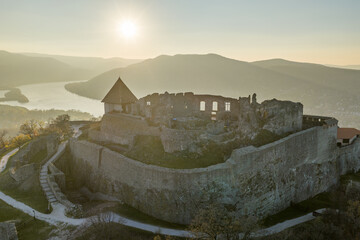 Visegrad, Hungary - Aerial panoramic drone view of the beautiful high castle of Visegrad on a moody autumn sunset. Danube Bend (Dunakanyar) and amazing golden sunset at background.