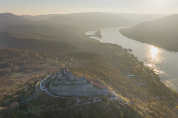 Visegrad, Hungary - Aerial panoramic drone view of the beautiful high castle of Visegrad on a moody autumn sunset. Danube Bend (Dunakanyar) and amazing golden sunset at background.