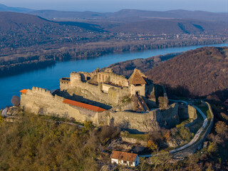 Visegrad, Hungary - Aerial panoramic drone view of the beautiful high castle of Visegrad on a moody autumn sunset. Danube Bend (Dunakanyar) and amazing golden sunset at background.