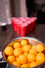 Party game setup, Playful indoor scene featuring ping pong balls and social accessories, Warmly lit indoor environment with beer pong essentials and lively social atmosphere
