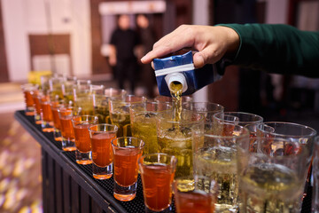 Vibrant party beverages, Festive setup with lively drink arrangements and busy bartenders, Array of layered shots and colorful cocktails ready for spirited gathering
