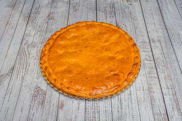 Traditional  Galician meat empanada, with its characteristic golden puff pastry crust sealed at the edges, presented whole on a pine board