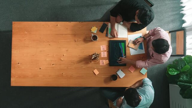 Group of diverse people sharing idea while writing at colorful sticky notes. Top down view of smart business team brainstorming idea and planning strategy for startup project. Time lapse. Convocation.