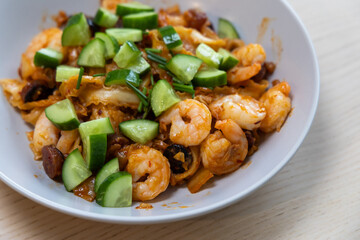 Close-up view of prawn noodles with cucumber.
