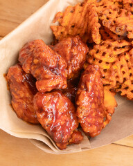 Saucy chicken wings served with waffle fries and fried plantain chips in a basket