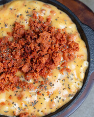 Baked macaroni and cheese topped with crispy bacon bits in a cast iron skillet