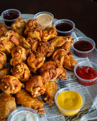 Fried chicken wings served with assorted dipping sauces on a paper-lined tray