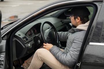 Male driver holding steering wheel of black car