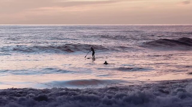 Wellenreiter auf der Suche nach der perfekten Welle bei Sonnenuntergang