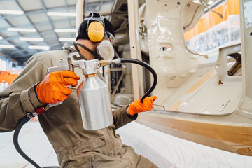 Specialist spraying anti rust sealant into the hidden chassis cavities. Protection against corrosion and internal body element sealing in a professional auto service shop
