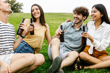 Happy young millennial group of diverse friends cheering with google beers and social gathering together at city park. Meeting and reunion concept