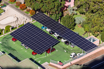 Car parking with solar panels. Top-down view of a parking lot with solar panel carports, several parked cars, and surrounding greenery