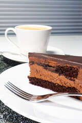 Chocolate mousse cake on plate in festive fashion style. Stylish dessert with sparkling detail and coffee. Indulgent treat