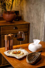 Restaurant table setting with wine and roasted pepper tzatziki