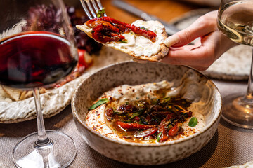 Woman tasting roasted pepper dip with wine