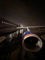 Russia, St.Petersburg, the plane is standing on the airport runway at night, many passengers are walking down the ramp to board the plane, a huge turbine on the wing of the aircraft
