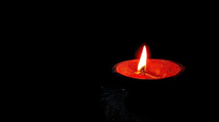 Single candle flame glows brightly in the darkness.