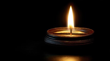 Single flame from a wick glows brightly in darkness.