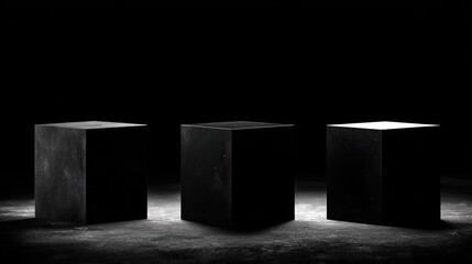 Three dark cubes are arranged on a textured surface under dramatic lighting.