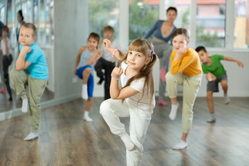 Obraz premium Girl learns to dance hip hop during childrens master class in studio. Teacher watches students, participates in training