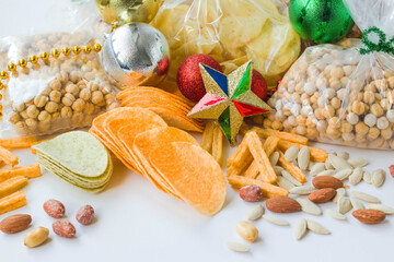 Mixed nuts in nylon packages white surface with christmas decorations and potato chips