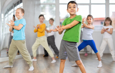 Fototapeta premium Children studying modern style dances with female teacher in dance class indoors