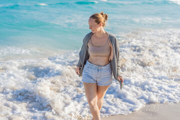Woman enjoying peaceful time at the beach, relaxing on the sand with ocean views and warm sunlight. Summer leisure, wellbeing and travel concept, representing freedom, calmness and mindful coastal