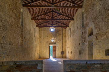 Interior of the Pieve di San Giovanni, Campiglia Marittima, Tuscany, Italy. The rough stone walls and exposed wooden truss roof define Romanesque simplicity