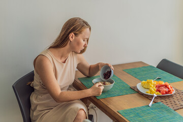 Woman enjoying a peaceful breakfast at the table in a bright home interior, starting her morning with calm energy. Healthy lifestyle, morning routine and wellbeing concept, representing self-care