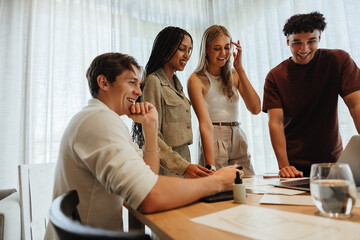 Young professionals collaborating on a project during a lighthearted office meeting