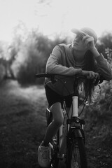 Dynamic Black and White Shot of a Young Woman Resting on a Mountain Bike in a Shadowy Forest During an Off-Road Ride