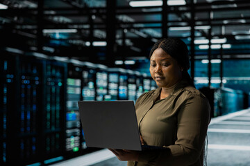 Admin using laptop to implement security measures integral to fortifying data center defenses against cyber threats. Server farm IT professional doing threat detection, defending company systems