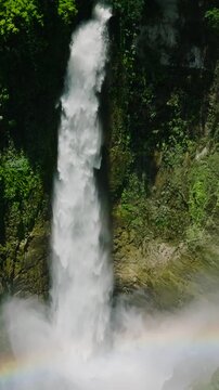 Rainbow over the water mist and splash of Hikong Bente Falls in Lake Sebu. Mindanao, Philippines, Vertical view and slow motion.