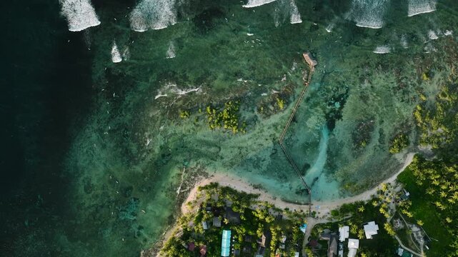 Aerial view of turquoise reef and pier stretch from the sandy coast into the sea. Siargao, Philippines. Cloud 9 Surfing Area.