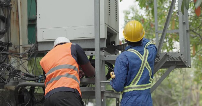Telecom engineer and technician inspect communication equipment during network maintenance and upgrade operation. Infrastructure inspection, troubleshooting, cable management for reliable connectivity