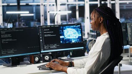 Data center female programmer using machine learning algorithms to analyze datasets. African american woman in server farm using AI neural networks to recognize data patterns, camera A