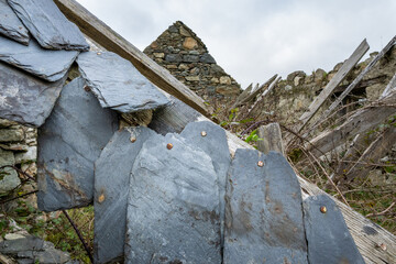 Ancient farm building with collapsed roof, closeup of slate tiles and rusty nails, as a background
