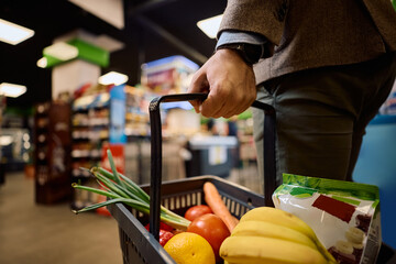 Close up of man with shopping basket full of groceries at store.