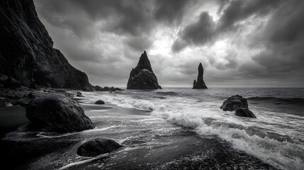 Dramatic black and white seascape captures towering rock formations against a stormy ocean horizon.