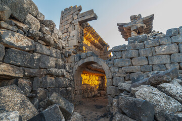 Umm Al-Jimal Sunset: Golden hour on the ancient black basalt ruins in Mafraq, Jordan. Roman tower contrasts with modern cell towers.