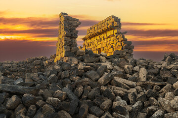 Umm Al-Jimal Sunset: Golden hour on the ancient black basalt ruins in Mafraq, Jordan. Roman tower contrasts with modern cell towers.