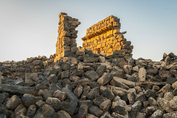 Umm Al-Jimal Sunset: Golden hour on the ancient black basalt ruins in Mafraq, Jordan. Roman tower contrasts with modern cell towers.