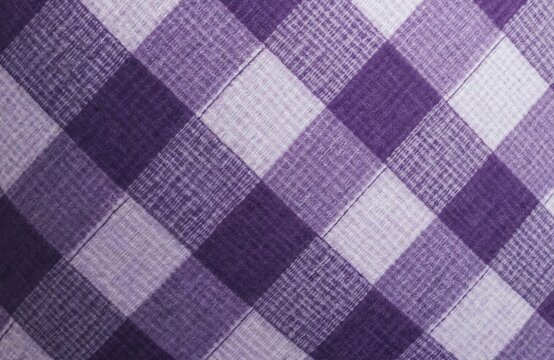 Close-up of purple plaid fabric with subtle weave. Texture forms diagonal checkered pattern in varying shades of lilac, deep violet. This textile offers cozy, traditional feel for backgrounds, decor. - Powered by Adobe